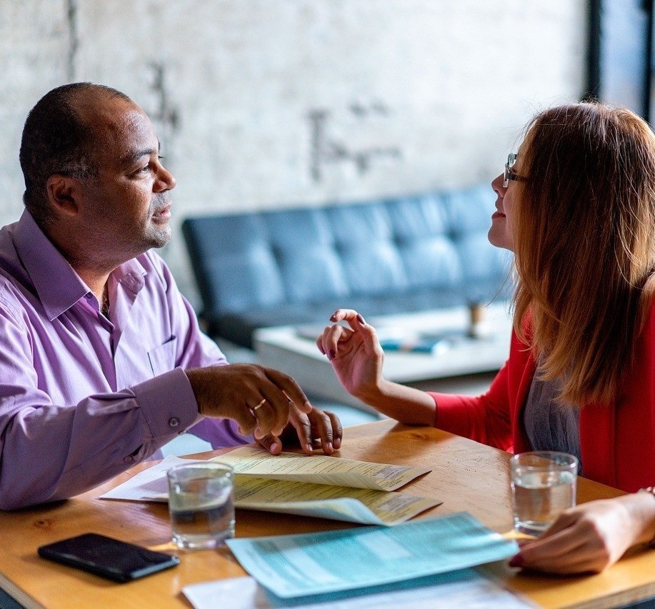 Two people sitting at a lunch table with papers chatting