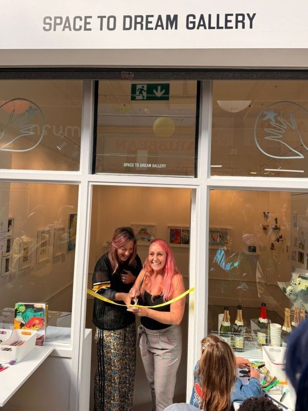 Photograph of Morgane and Fran, the gallery's co-founders, cutting the ribbon on opening day of the Space to Dream Gallery last year, September the 13th, 2025.