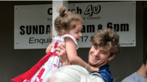 Man holding child in front of church4u