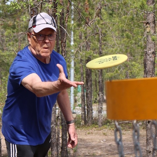 Mies pelaa frisbeegolfia Virkeiden Ikämiesten tapahtumassa.