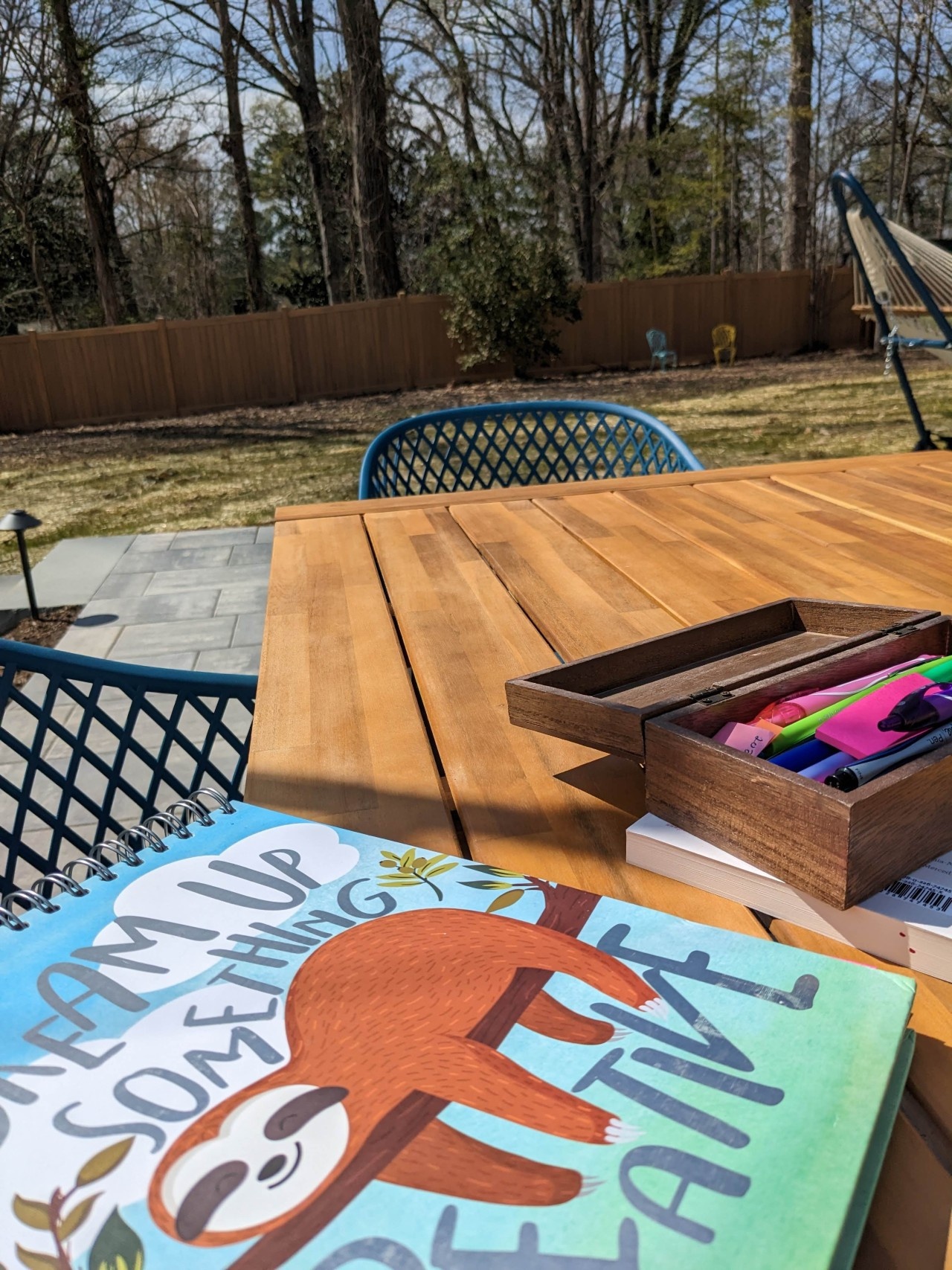 journal and pens on wood table; yard and fence in background