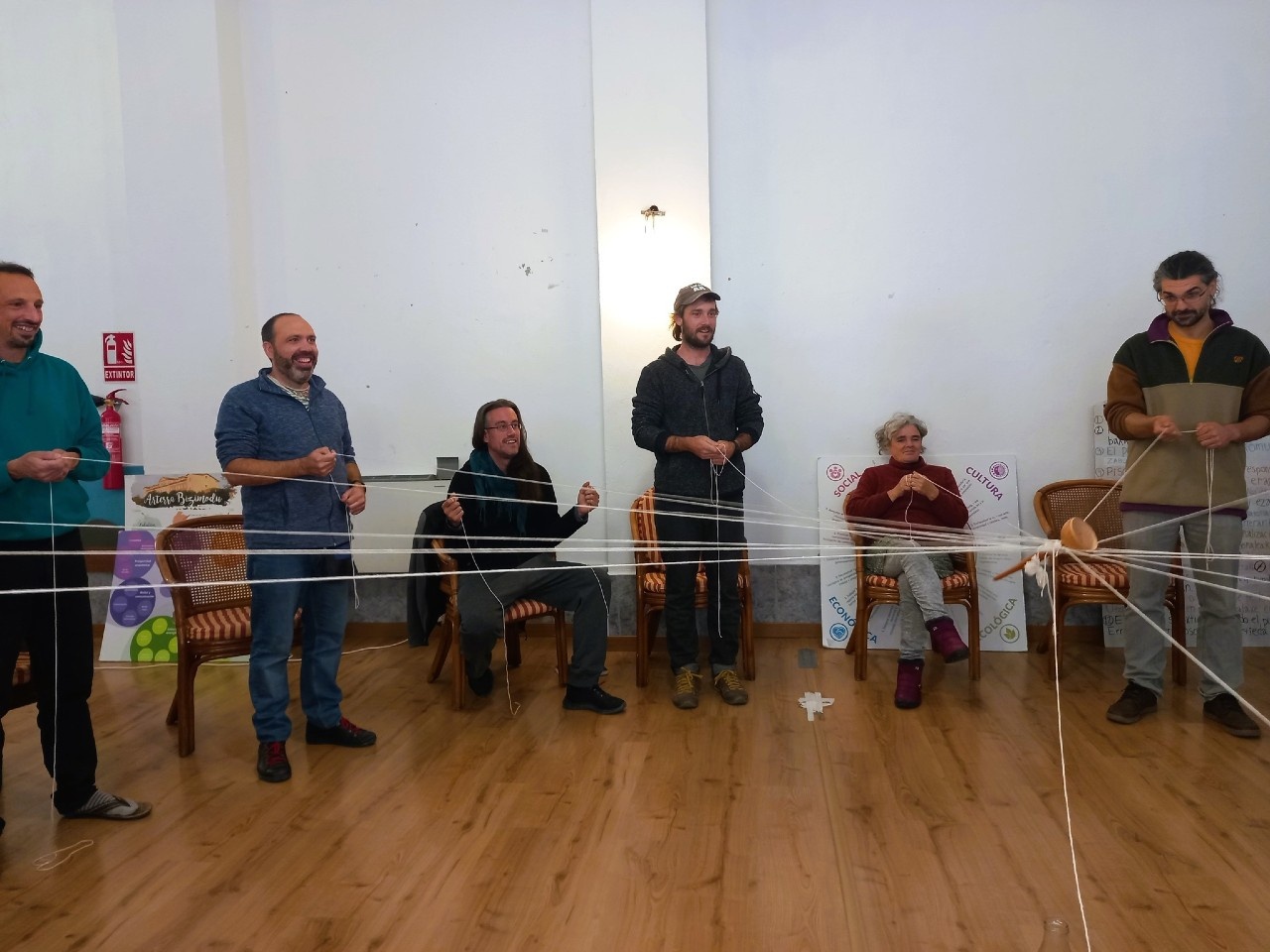 Arterranas sosteniendo una pieza de madera con cordeles