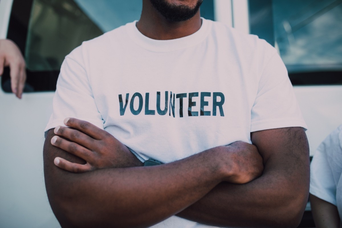 Torso of a man with his arms crossed with 'Volunteer' written on his t-shirt.
