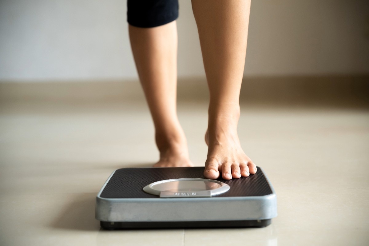 A foot tentatively steps on a set of weighing scales