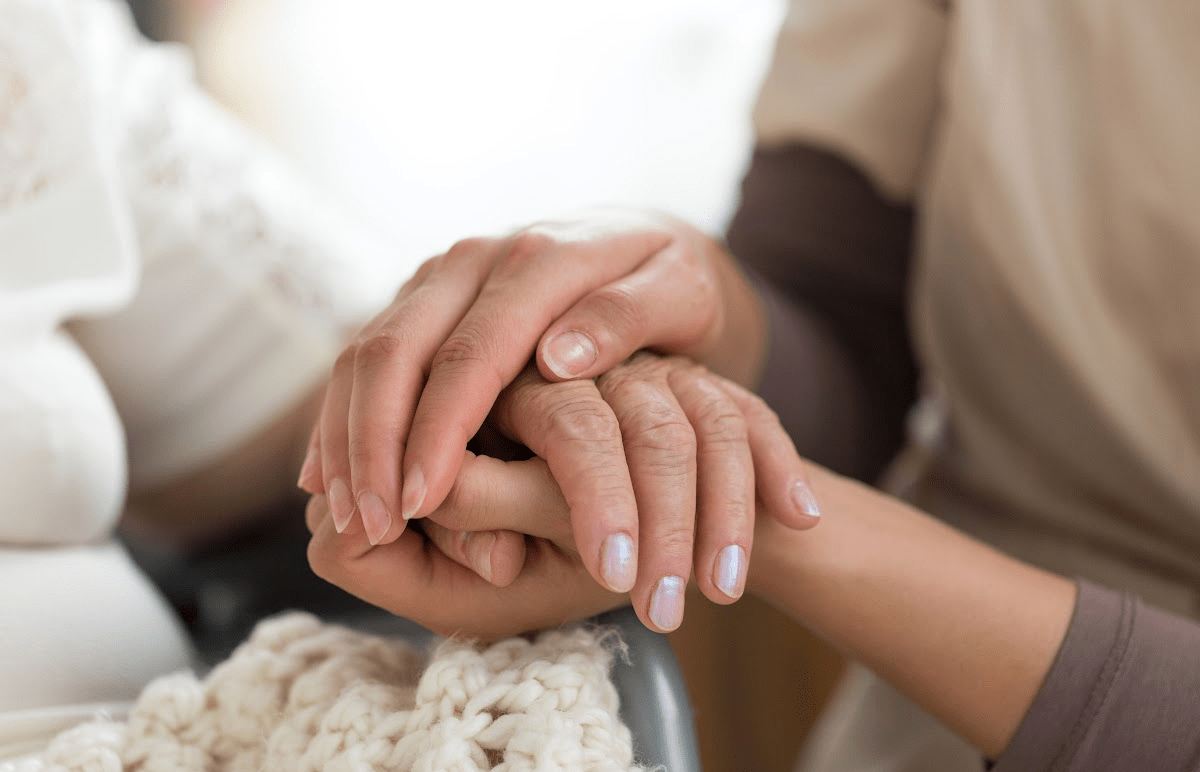 Close up of a person clasping another persons hand in a comforting way