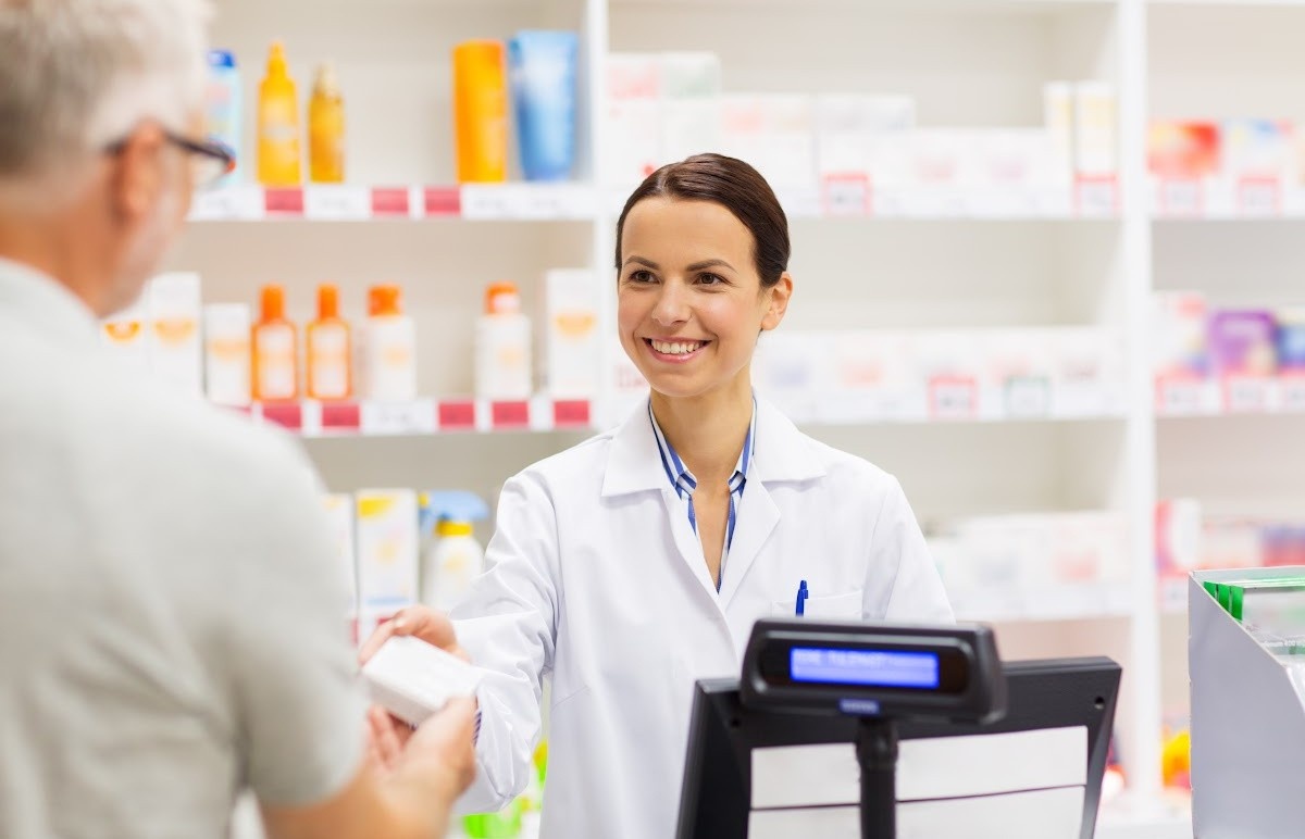 A pharmacist smiles as an elderly customer
