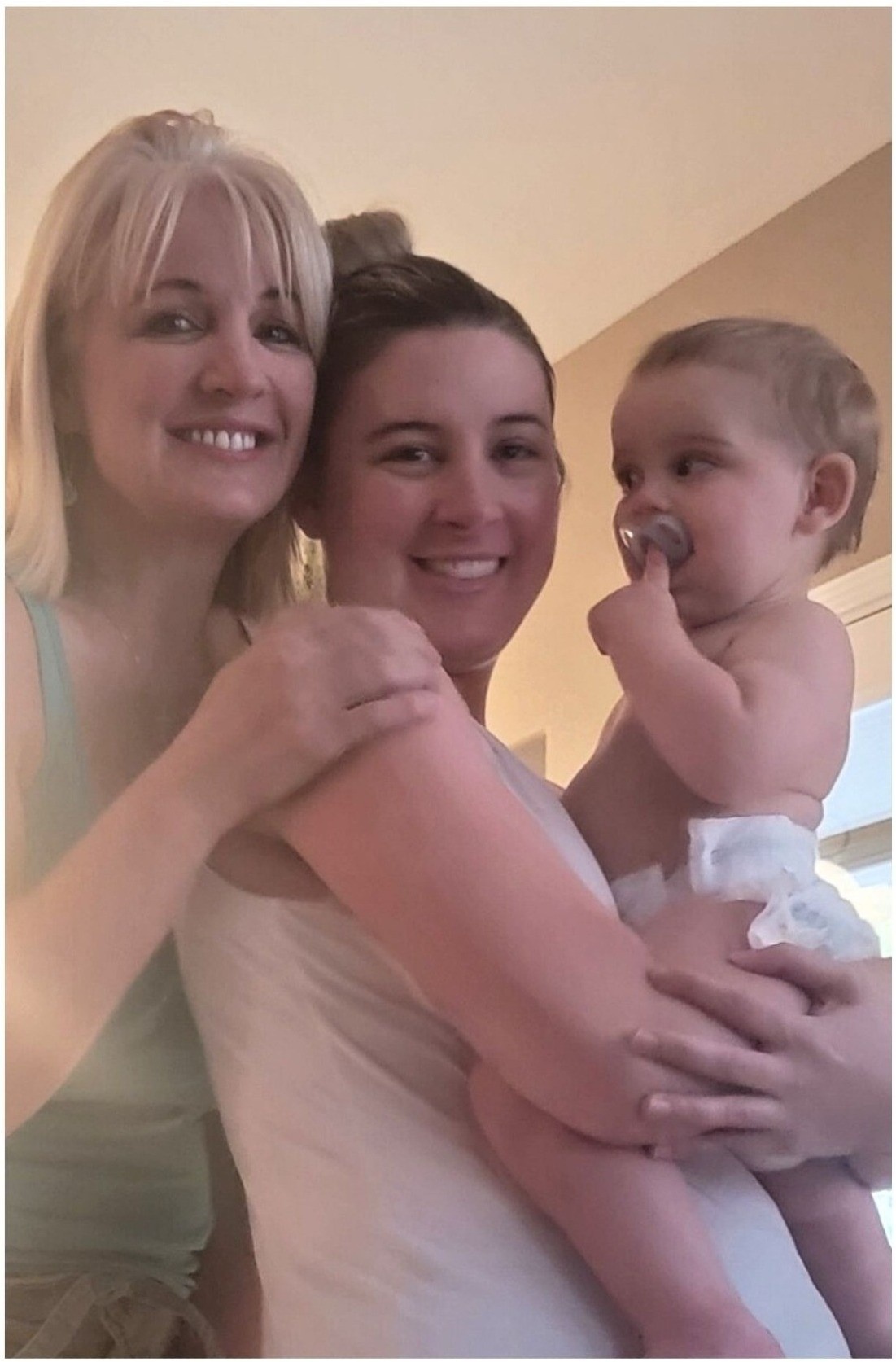 Renee smiling, hugging another woman with her baby.