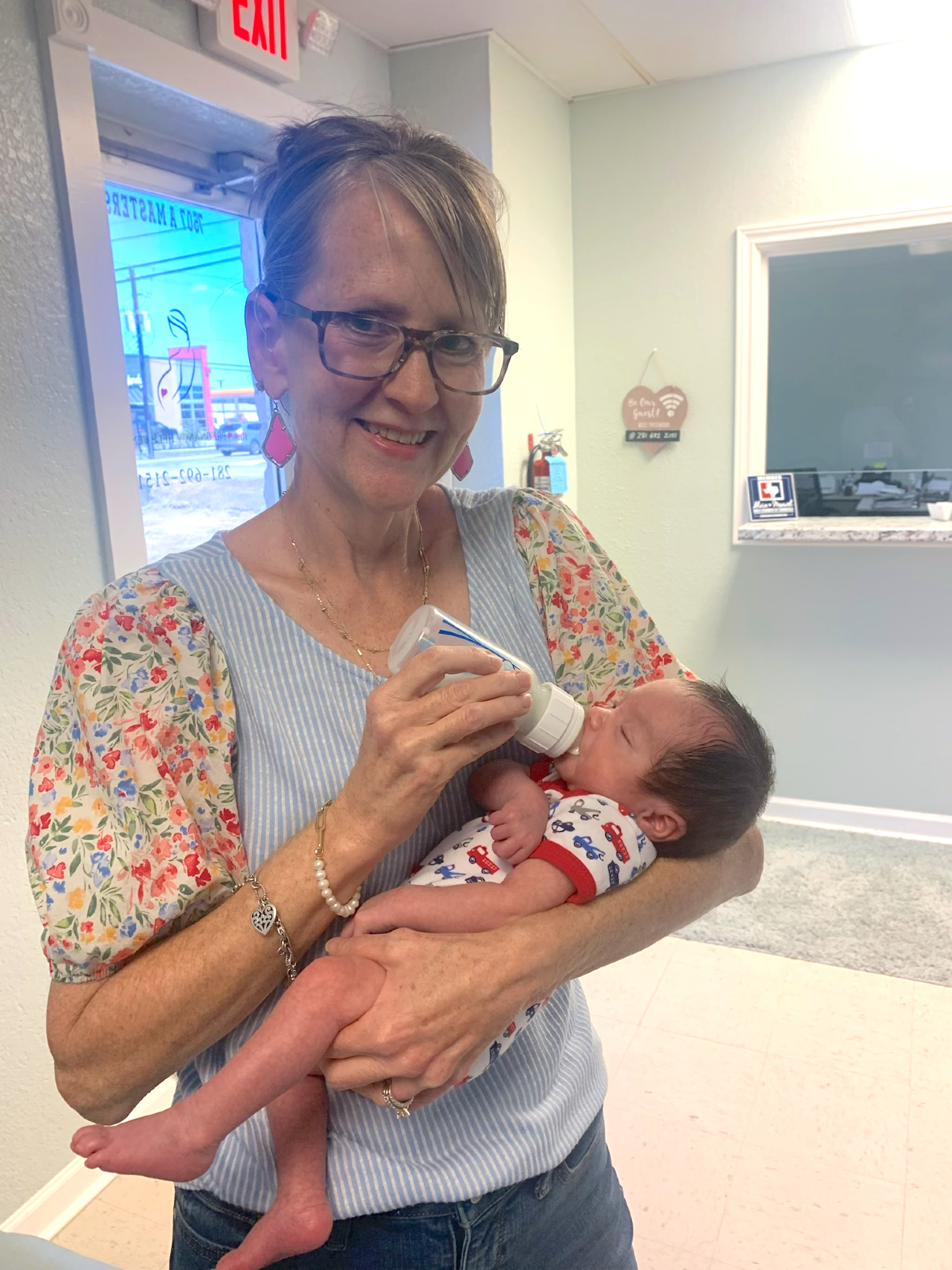 Mrs. Anne pictured holding a small baby with a bottle