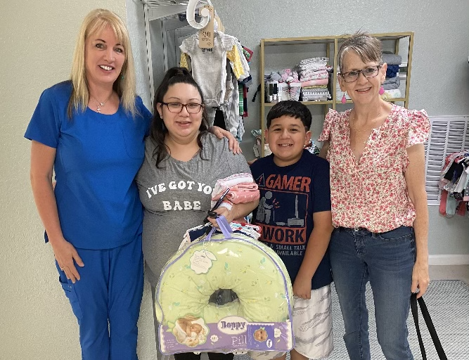 Ms. Anne pictured giving baby clothes and other equipment to a mother with Renee Arriaga.