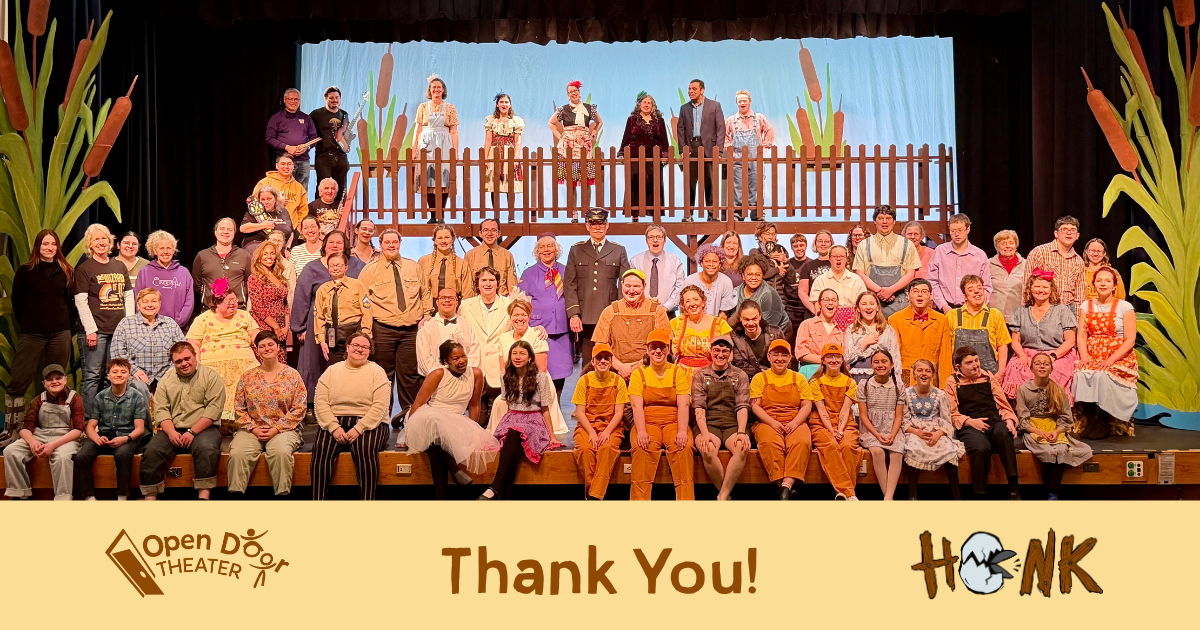 Actors in colorful farm themed costumes and crew members stand together on a brightly lit stage with a platform in the background and oversized green and brown cattails framing the stage.