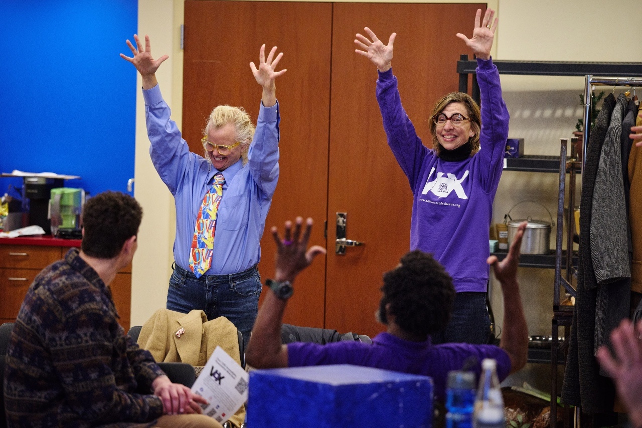 Sabrina and Kristin with Deaf applause/waving hands during Vox's accessibility training.