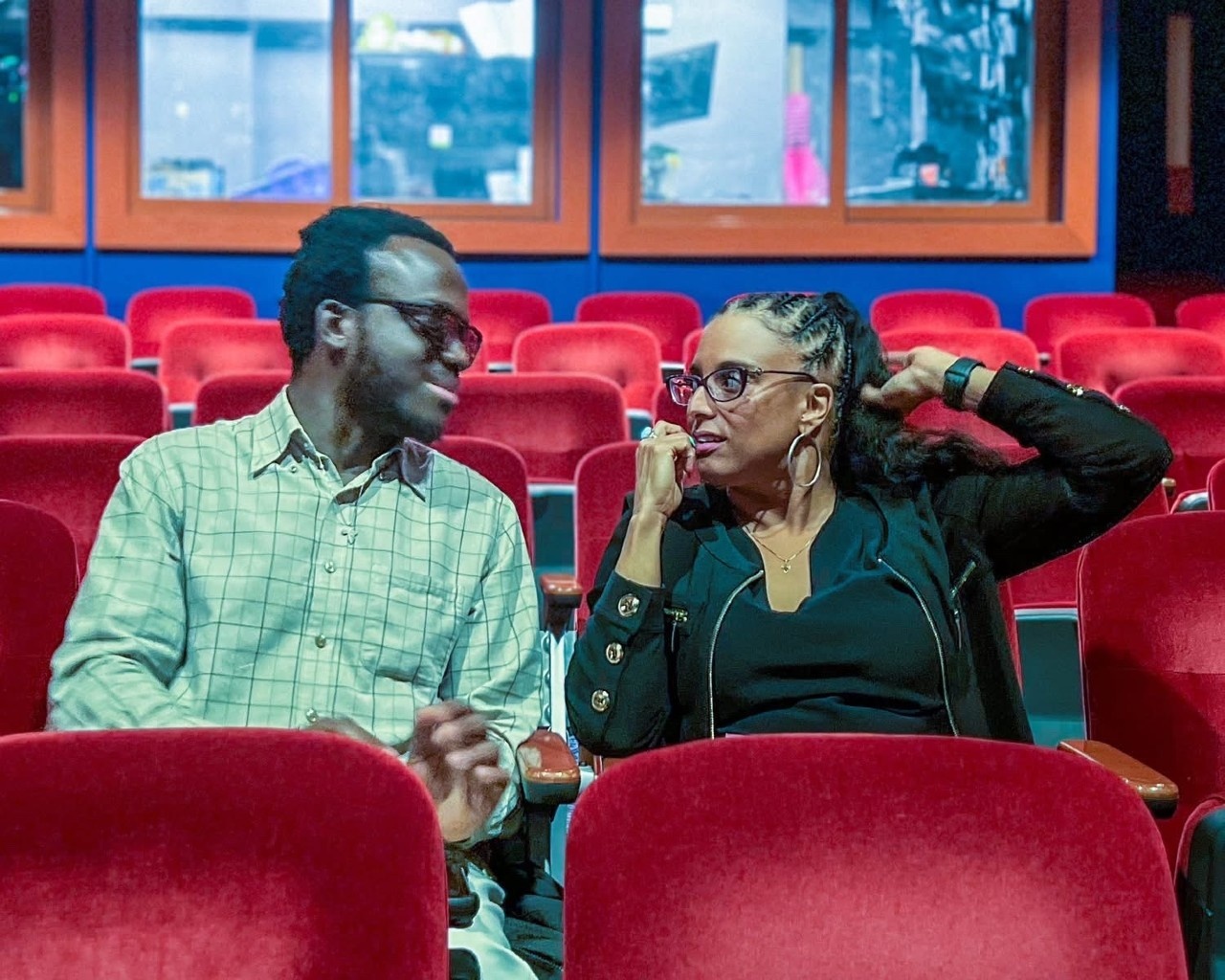 Kwaku and Maria sit in the seats discussing the show.