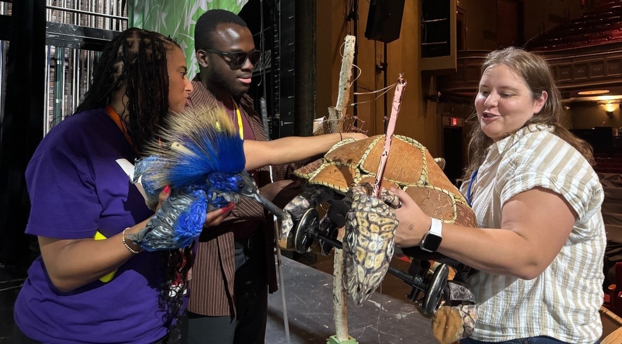 Kwaku and Maria explore Turtle as Stage Manager Amanda holds her up on stage.