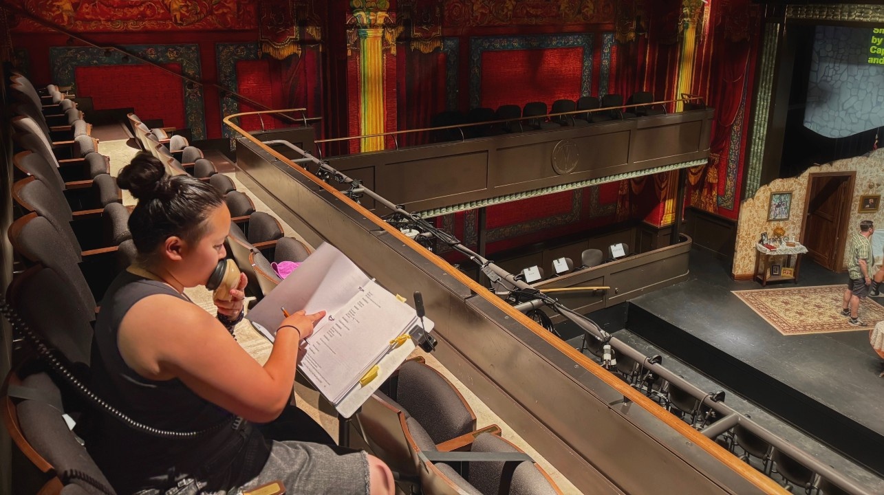 Jae in the balcony of The Modern Theater practicing their in-show audio description.