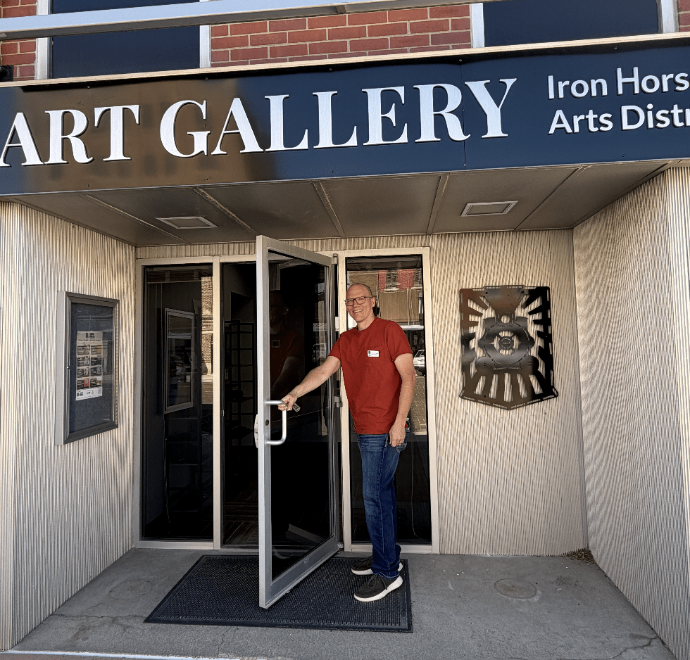 A man in a red shirt opens the door to the Iron Horse Art Gallery & Office space.