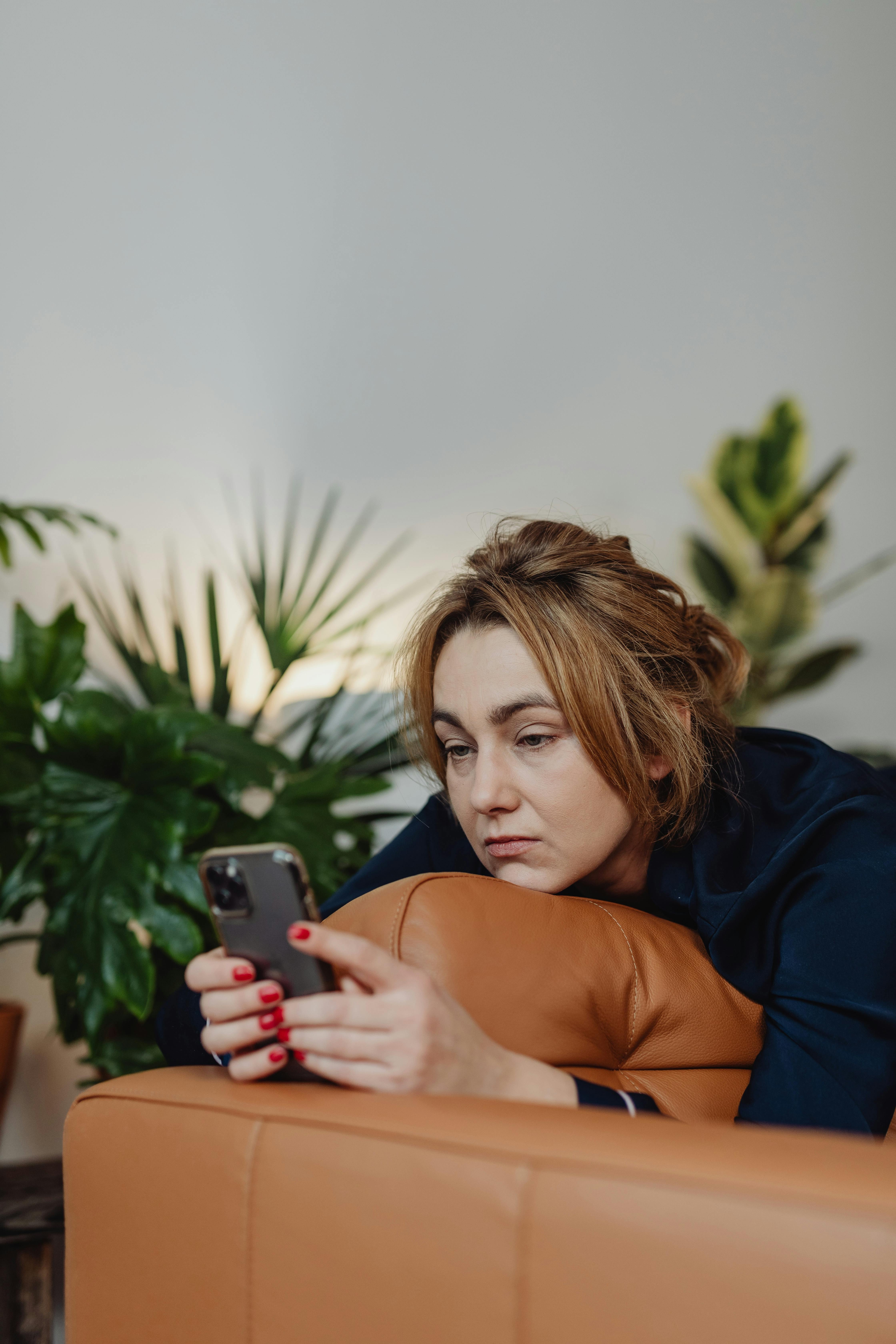 women looking at her phone stressed out on sofa with brown hair