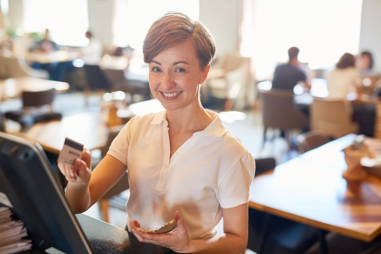 Woman cashing up an order - image from the front of the Developing Leaders for Hospitality and Tourism brochure