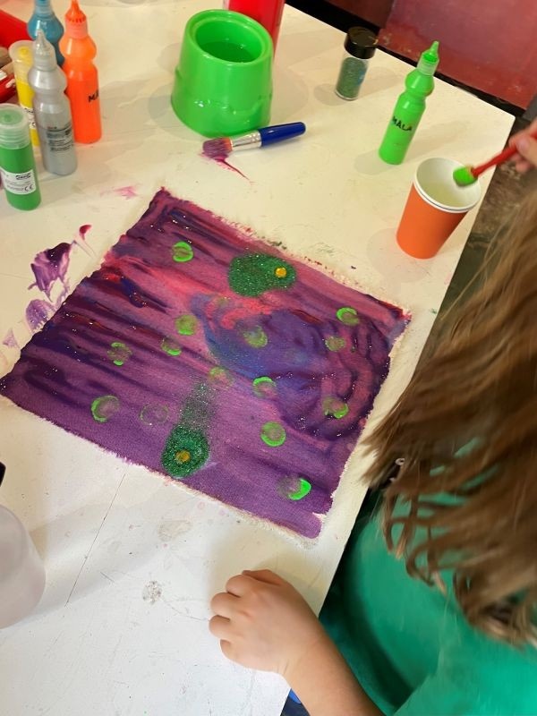 5 children working on individual canvases around a central table. To the right, Susi and Frederik, from Sir Frank Bowling's studio, are visible.