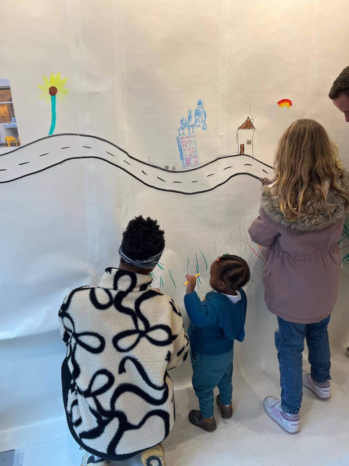 Parents and children drawing at different levels of our collaborative mural.