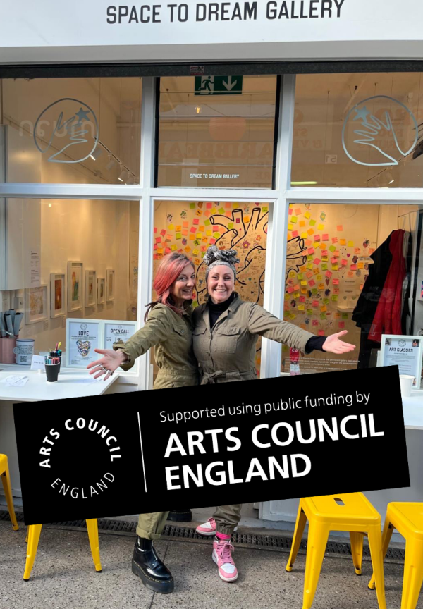Morgane and Fran, both our co-founders, are standing in front of the Space to Dream gallery with arms outstretched. They are widely smiling. The photograph is stamped with Arts Council England's logo.