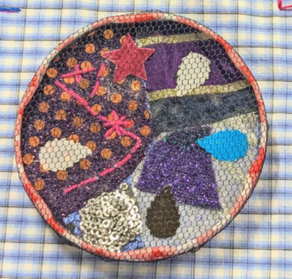 Close-up shot of one handmade giant couture button, using different pieces of fabric, felt shapes, sequins and embroidery amongst other things.