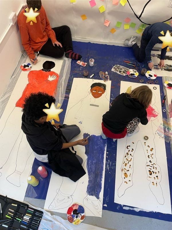 Photograph taken during one of our art classes. Four students work on life-size self-portraits on the floor of the gallery
