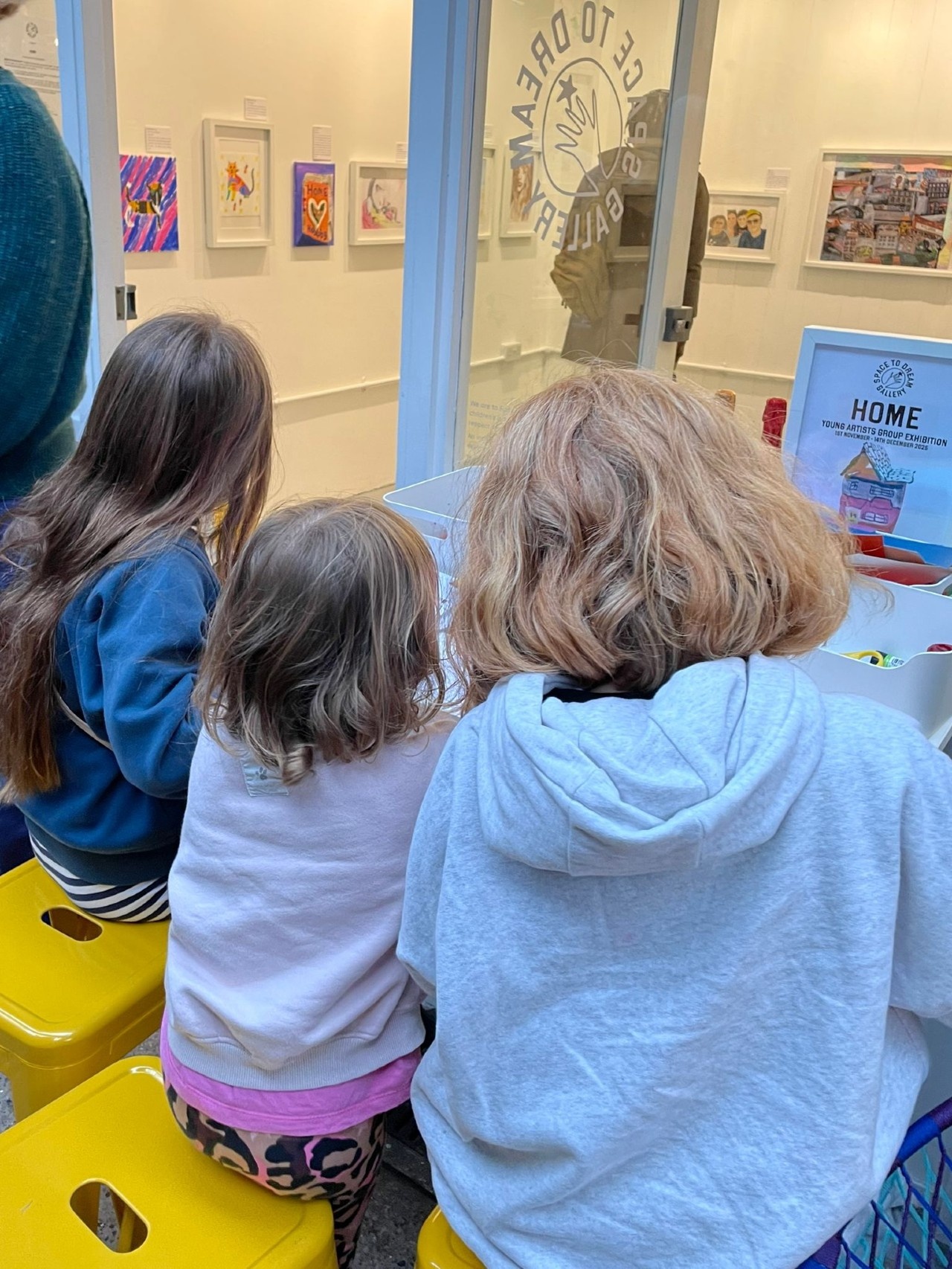 Three young girls drawing outside the Space to Dream gallery on the opening of the new exhibition at the Space to Dream Gallery.