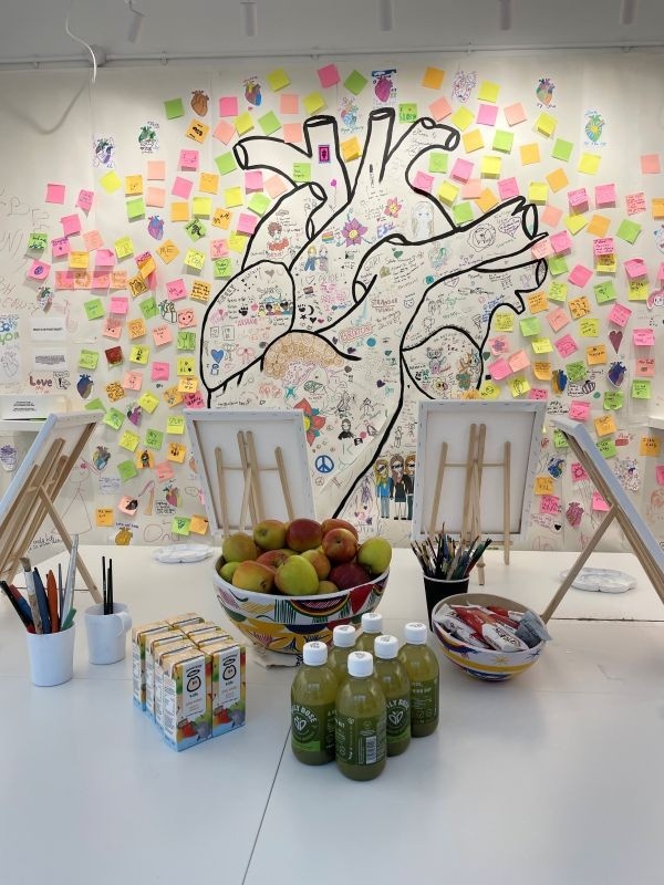 Photograph of the snacks and juices provided by the charity Healthy Living Platform. The snacks are set on the table where small canvases have been set as well, ready for another term of art classes.