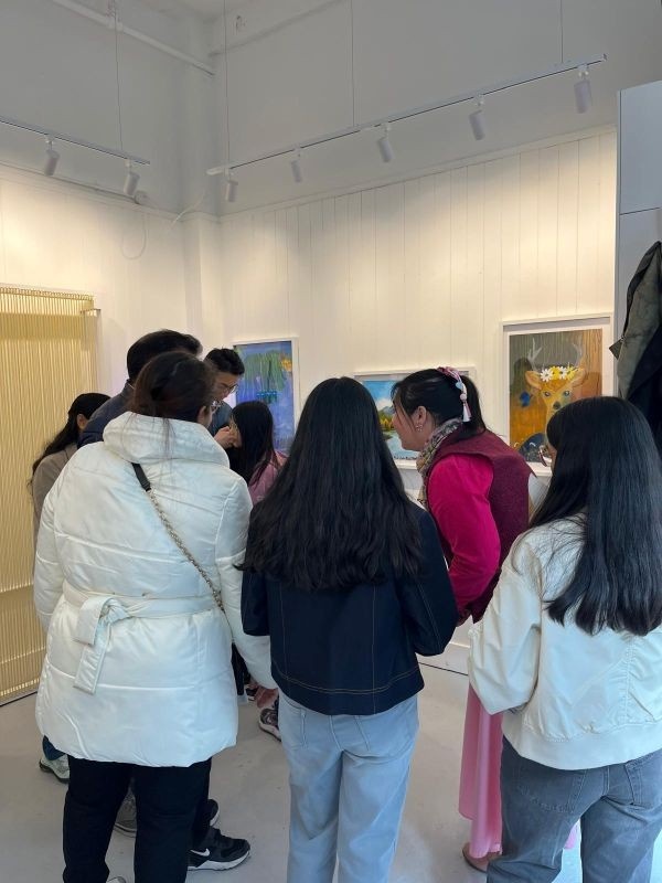 Photograph taken at the Space to Dream gallery on the opening of the new exhibition; LIFE. The gallery is busy, but we can make out three paintings hanging on one wall, as well as part of a giant loom fixed to the adjacent wall.