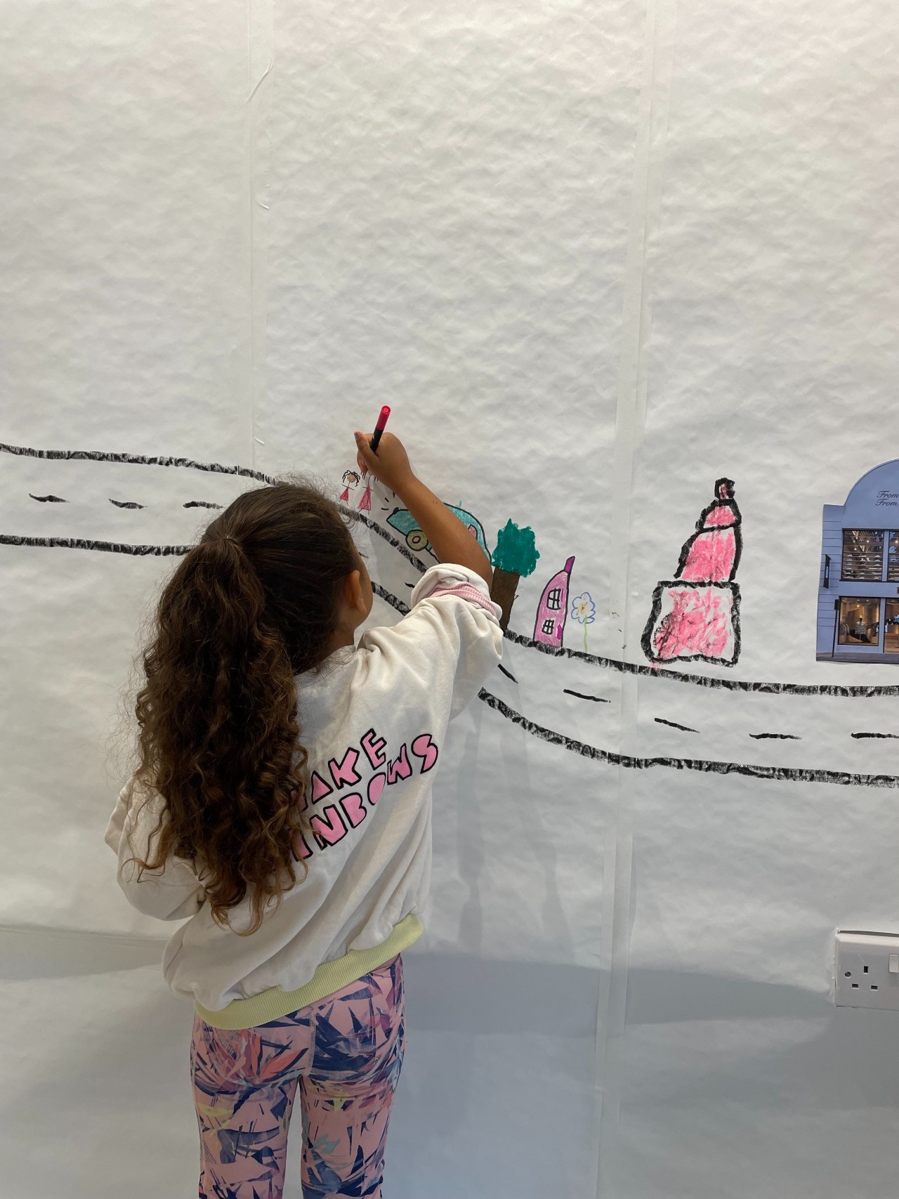 Young girl drawing a character as part of our collaborative mural.