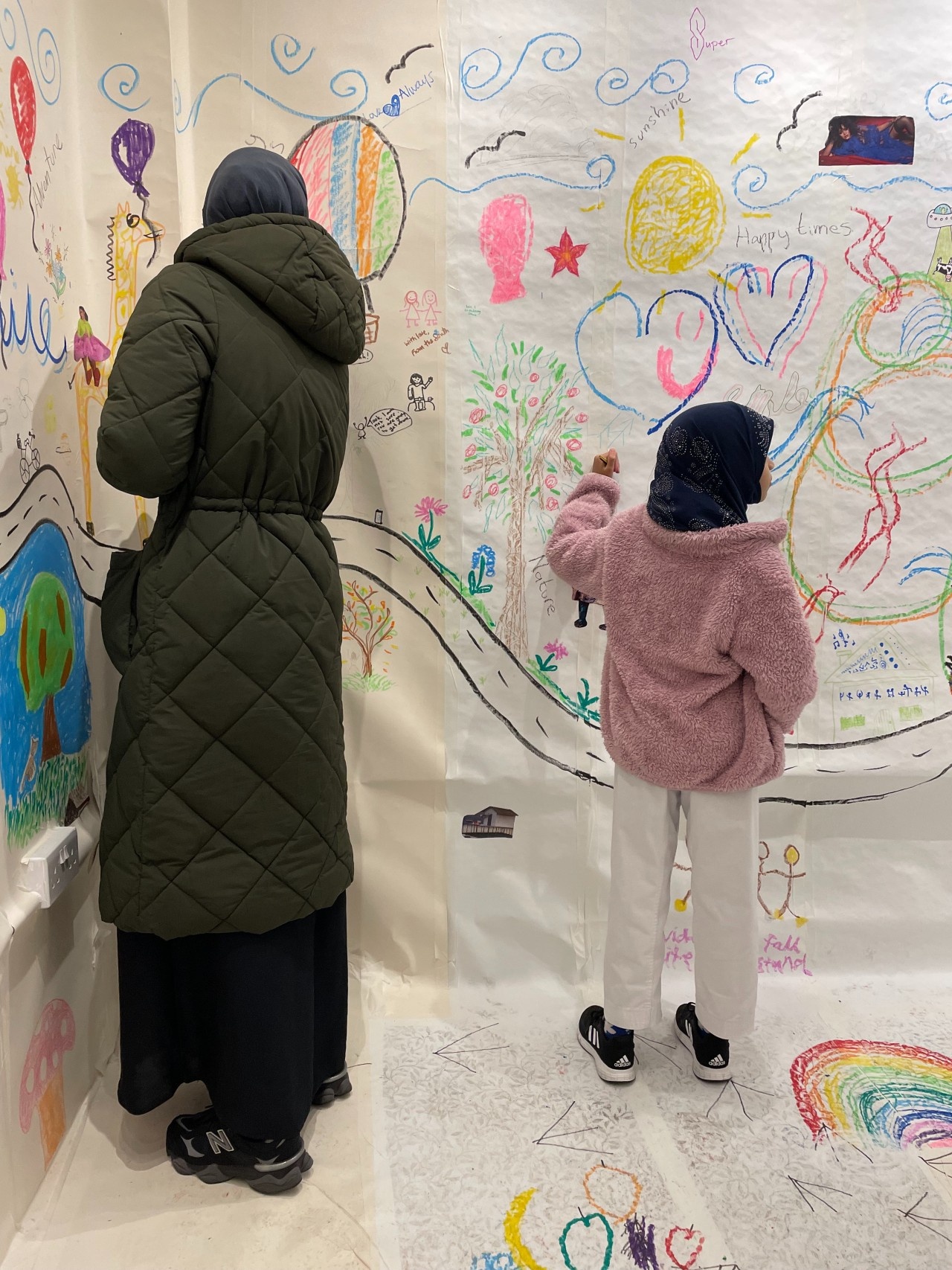 Woman and girl drawing on different parts of our collaborative mural.