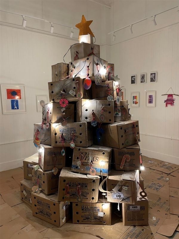 Poster for The Big Tree community Creative Project taking place at the Space to Dream Gallery on the 21st of December 2025 in the afternoon. It features an AI-generated photgraph of a giant Christmas tree made out of cardboard fruit boxes.