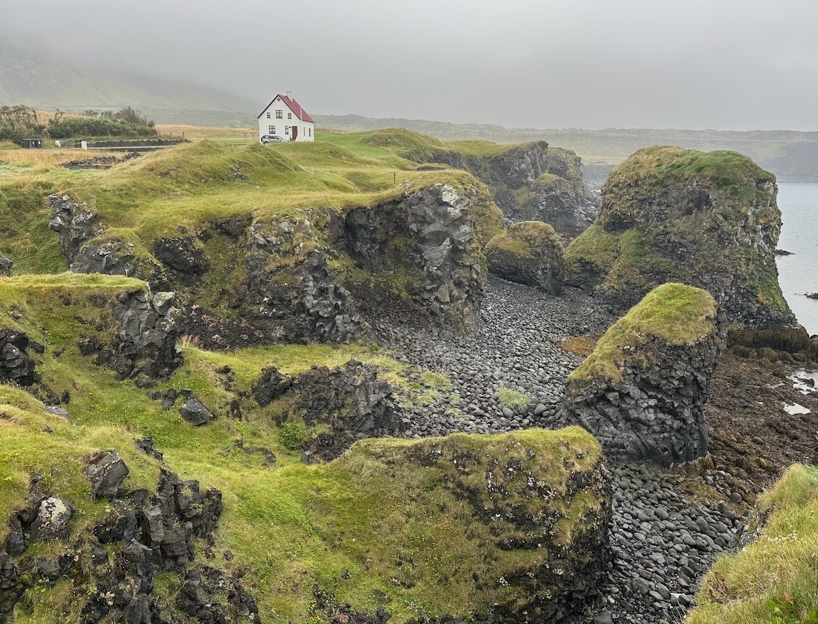 Arnarstapi Harbor in Snaefelssnes Peninsula, Iceland - misty skies, mossy and rocky beachside with a single white house