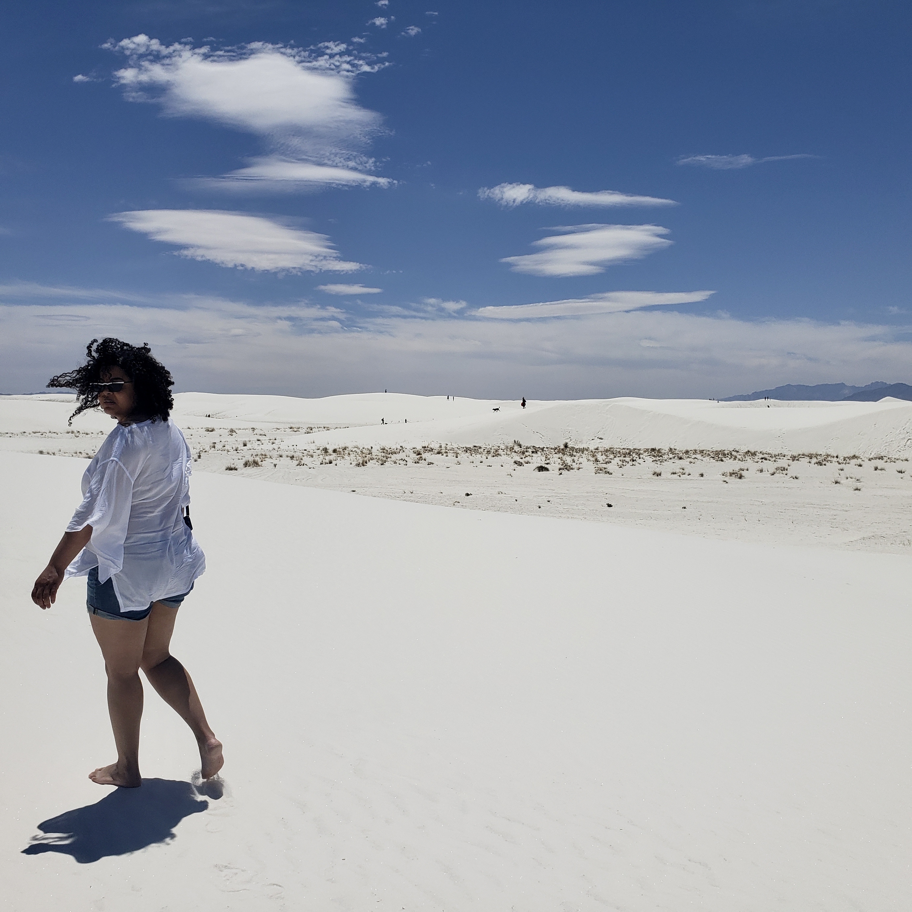 Woman walking away from camera on white sand dunes