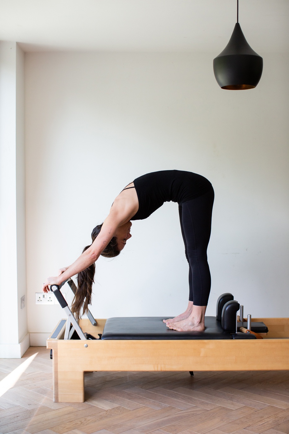 Deborah stretching forward on the Reformer in the studio