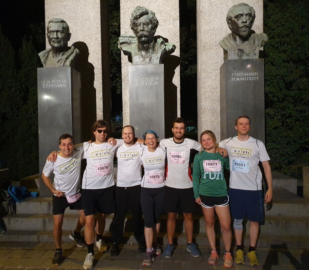 Bild: das VRVis-Laufteam beim Vienna Night Run 2023 vor einem Denkmal, das die Büsten von 3 Männern zeigt