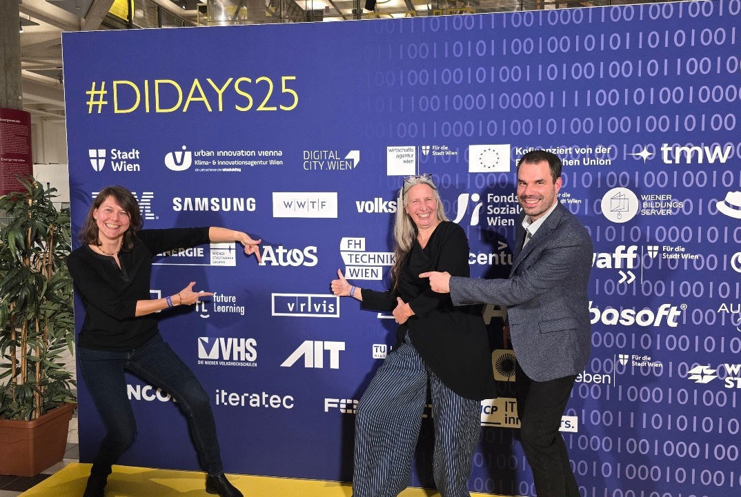Bild: das VRVis-Team steht vor der Sponsorenwand der Digital Days und zeigt auf das VRVis-Logo