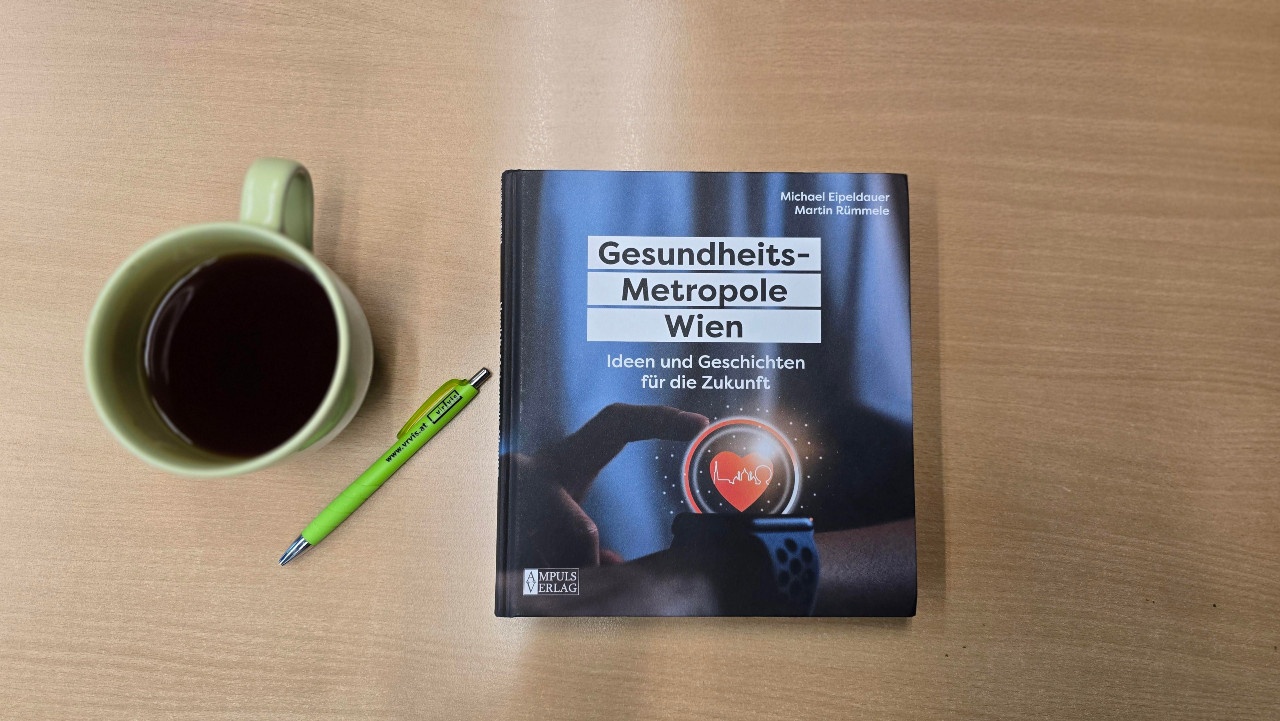 Bild: Das Buch "Gesundheitsmetropole Wien" auf einem Tisch liegend, daneben eine grüne Tasse und ein VRVis-Kuli